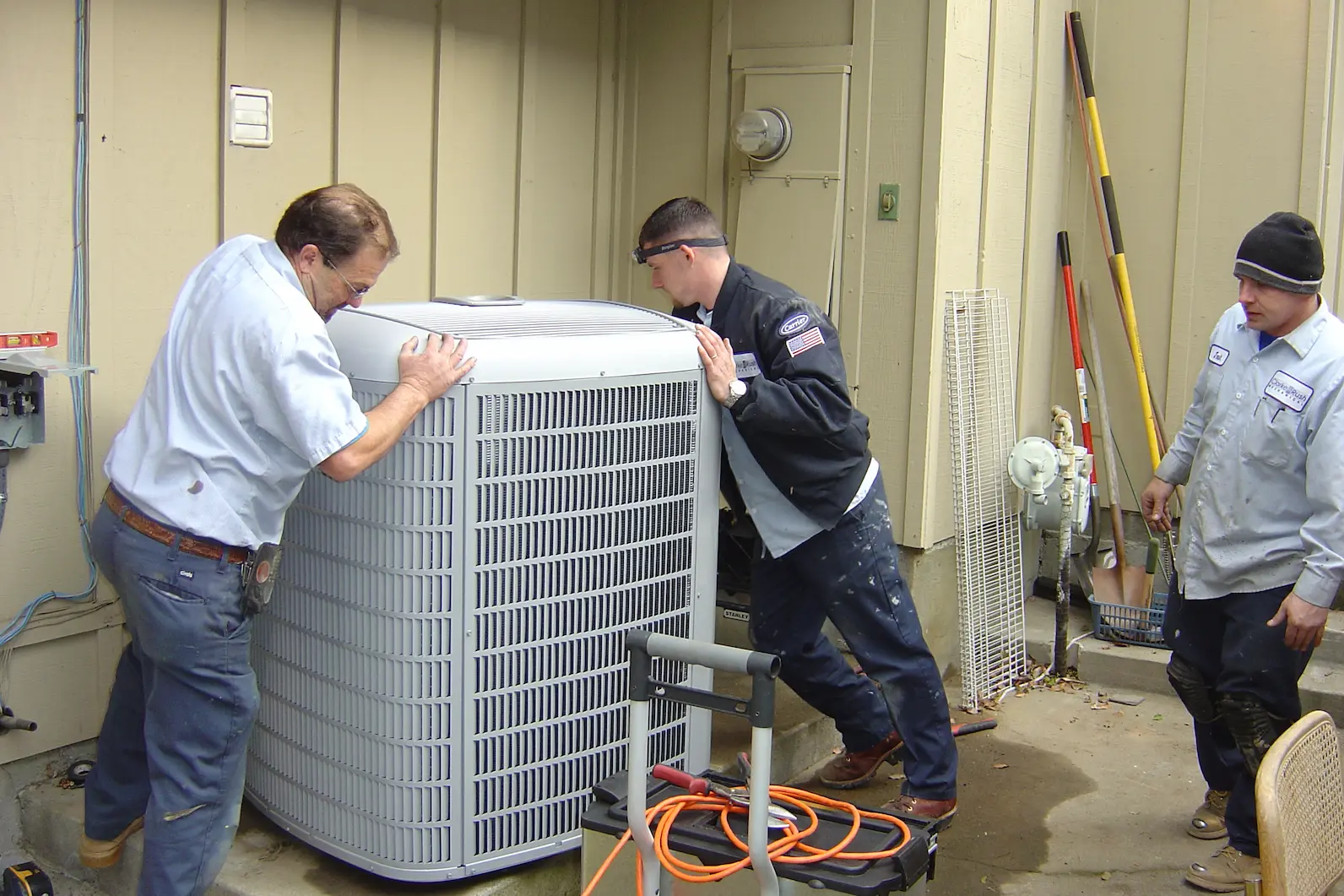 HVAC Services of two technicians reeling in an AC unit for installation